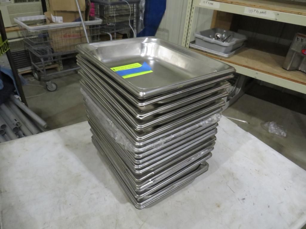 Stack of stainless steel food trays on a white surface, indoors.