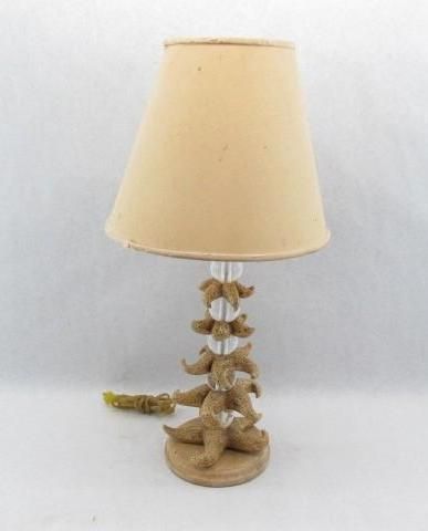 Table lamp with beige lampshade and starfish-shaped base on a white surface.