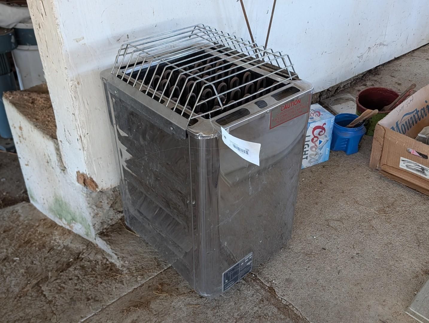 Metal stove or heater with grill top beside a white wall in a utility area