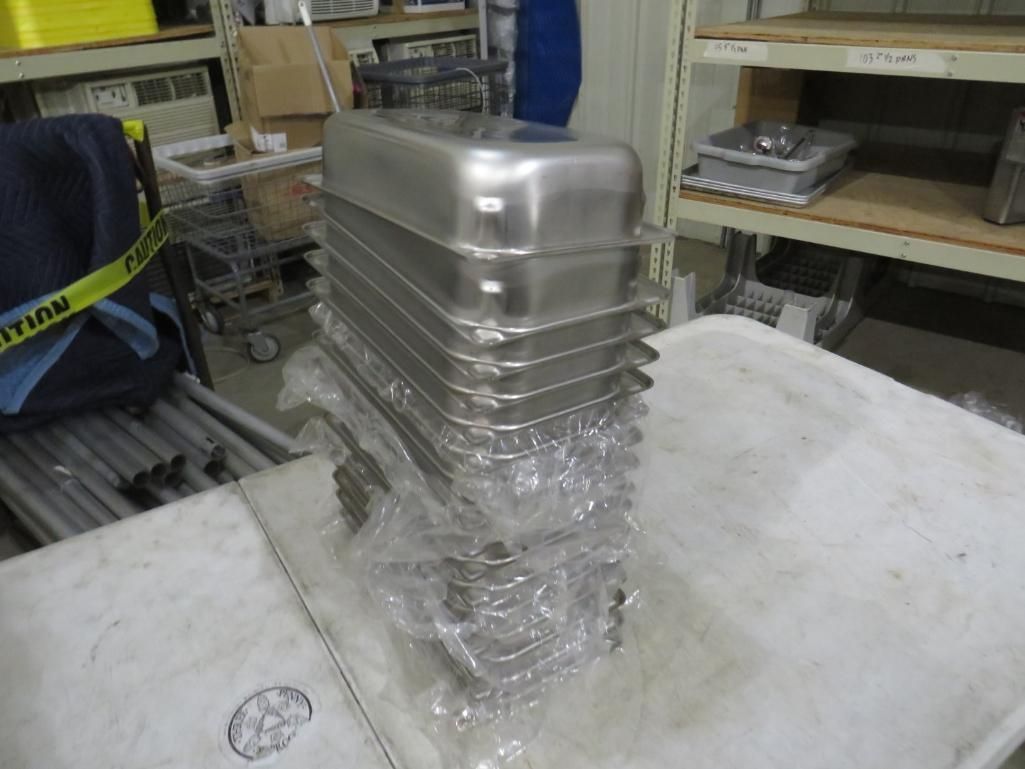 Stack of metal rectangular containers wrapped in clear plastic on a white cloth in a warehouse.