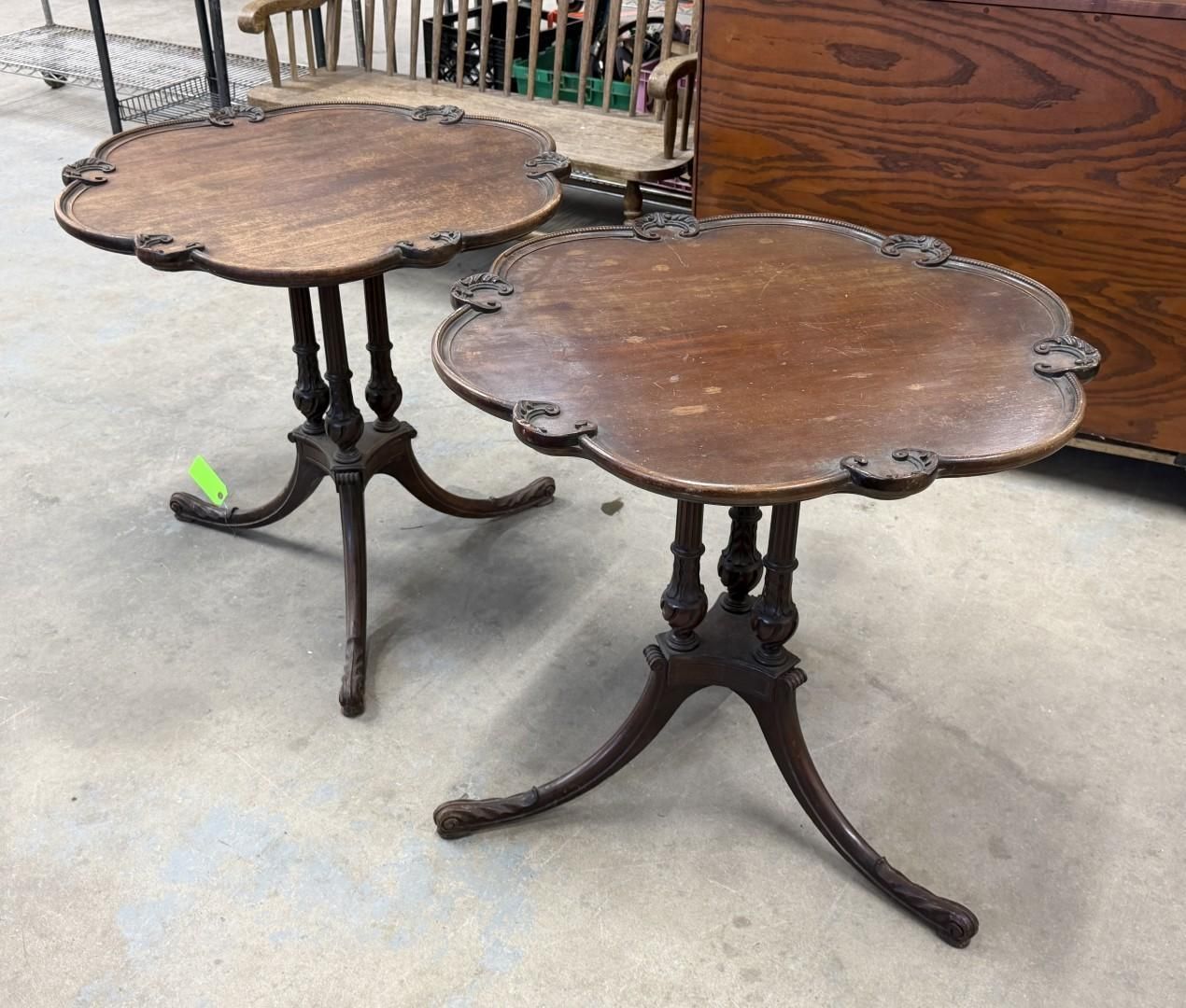 Two ornate, wooden side tables with scalloped tops and tripod bases.