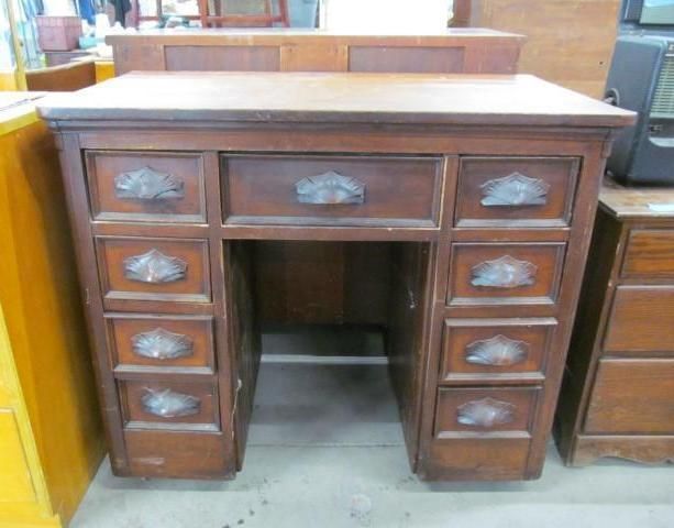 Wooden antique desk with drawers and ornate pulls.