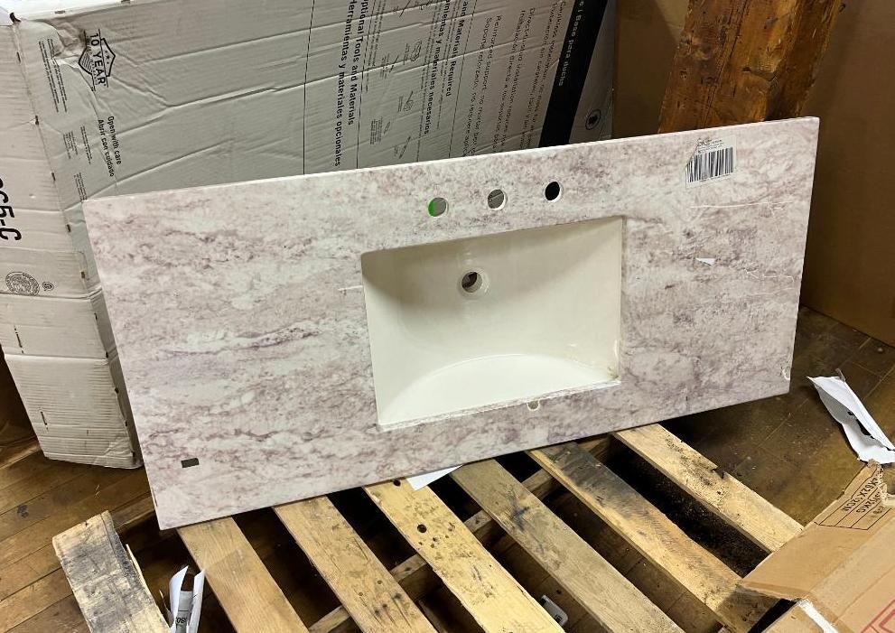 Tan and white vanity countertop with a sink and three faucet holes, on a wooden pallet.