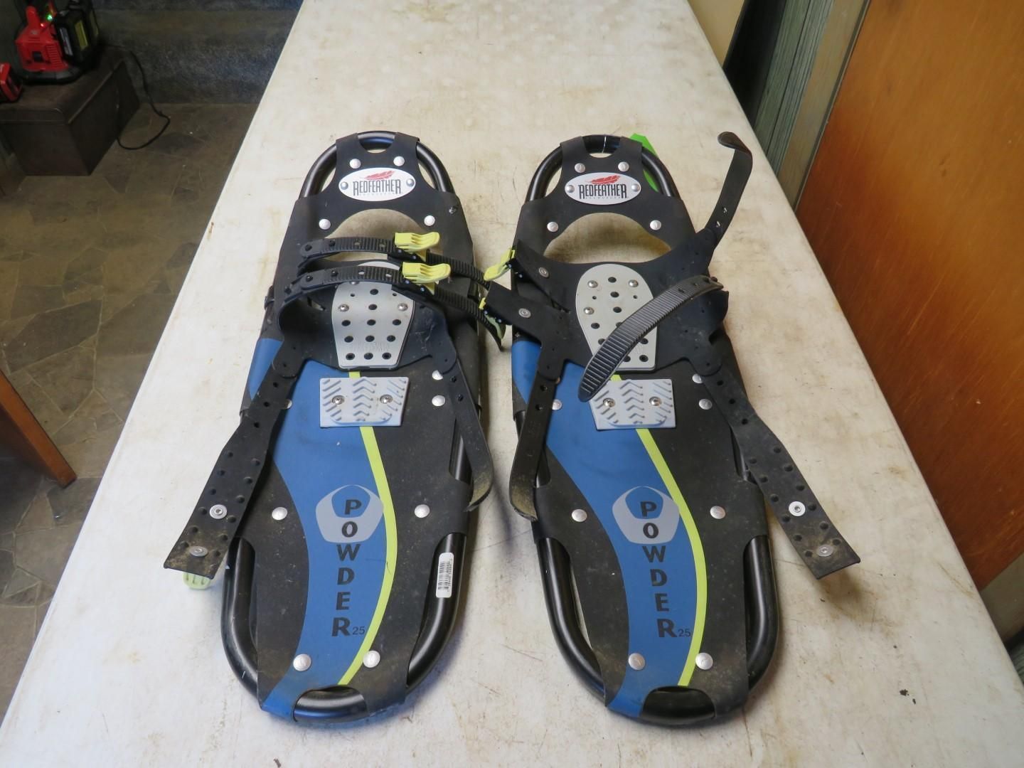 Pair of black and blue snowshoes on a white surface, with