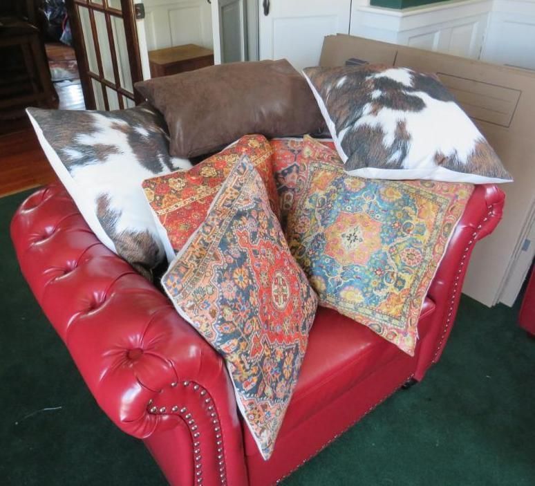 Red leather chair piled with decorative pillows, including cowhide and patterned fabrics.