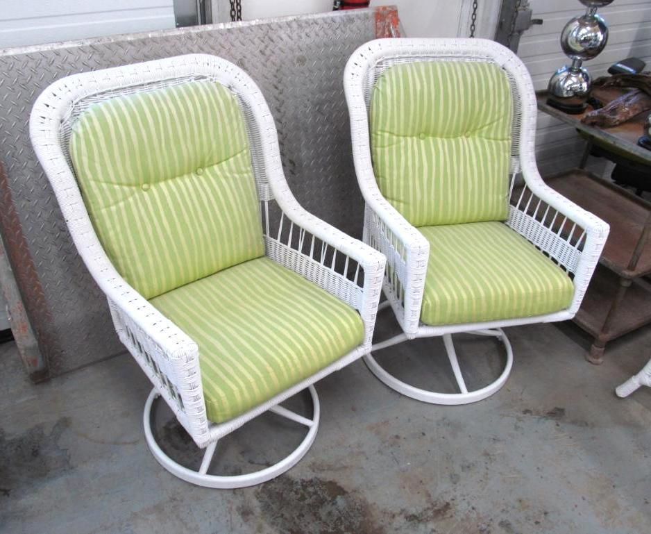 Two white wicker swivel chairs with green striped cushions.
