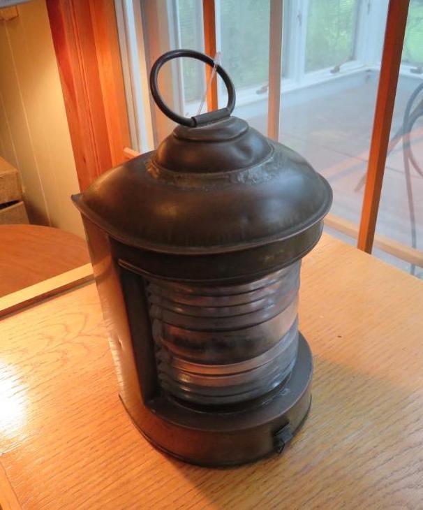 Antique brass ship lantern on a wooden table, window in background.