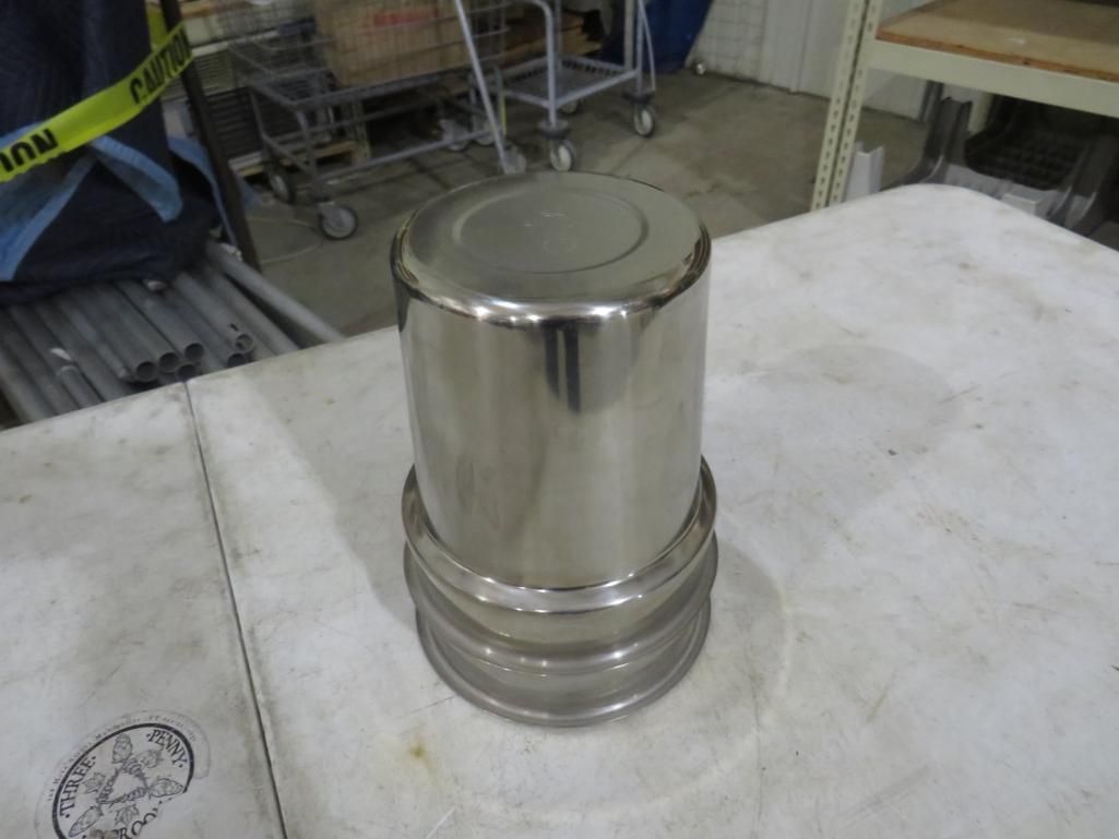 Shiny, cylindrical metal object with a flared base, on a white surface, indoors.