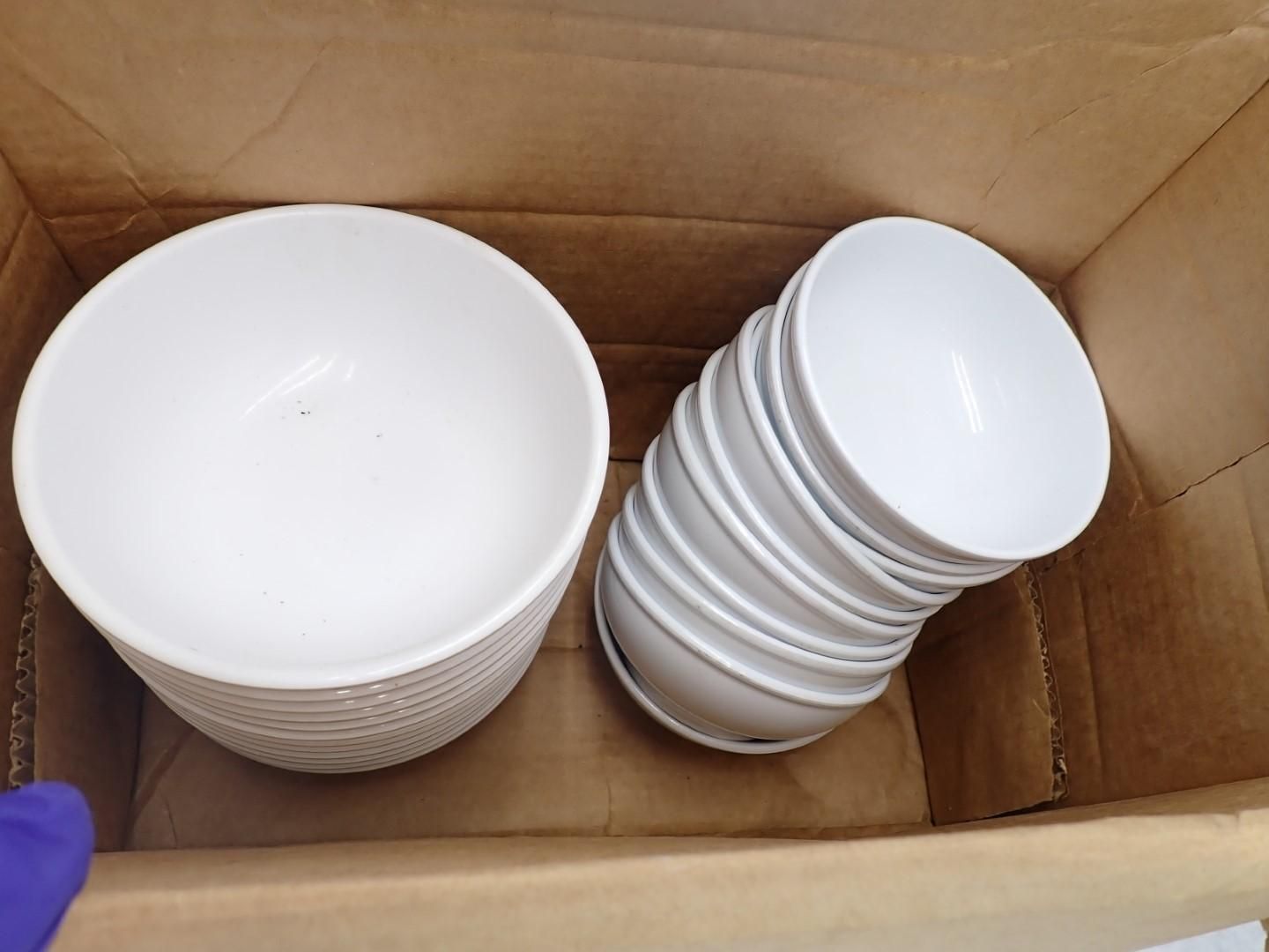 White bowls stacked in a cardboard box, ready for use or storage.