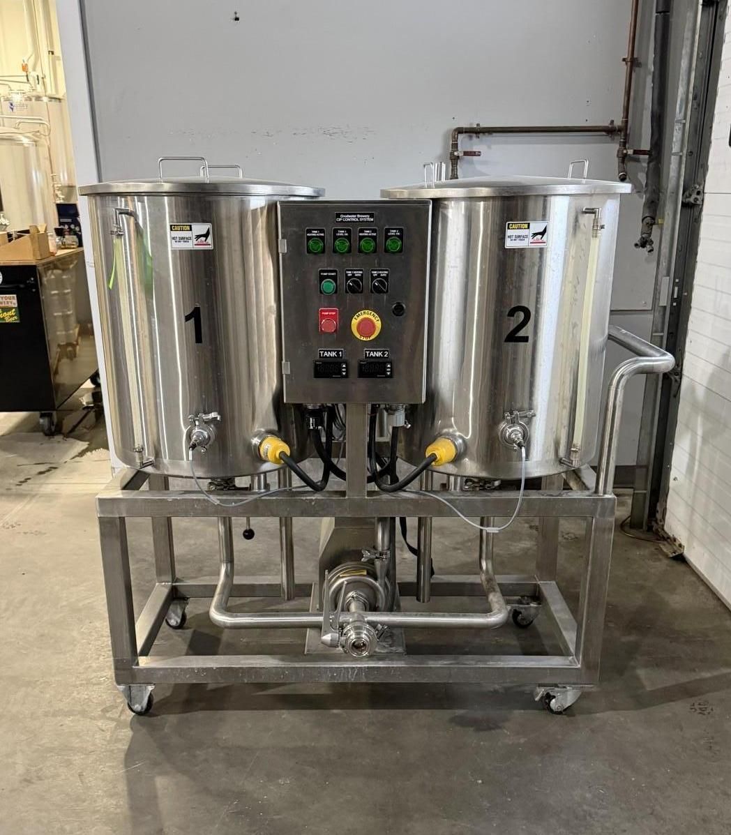 Stainless steel brewing system with two numbered kettles, control panel, and pump on a cart.