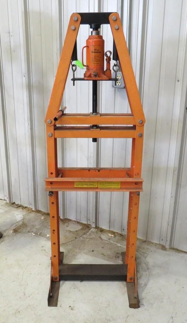 Orange hydraulic press in a workshop.