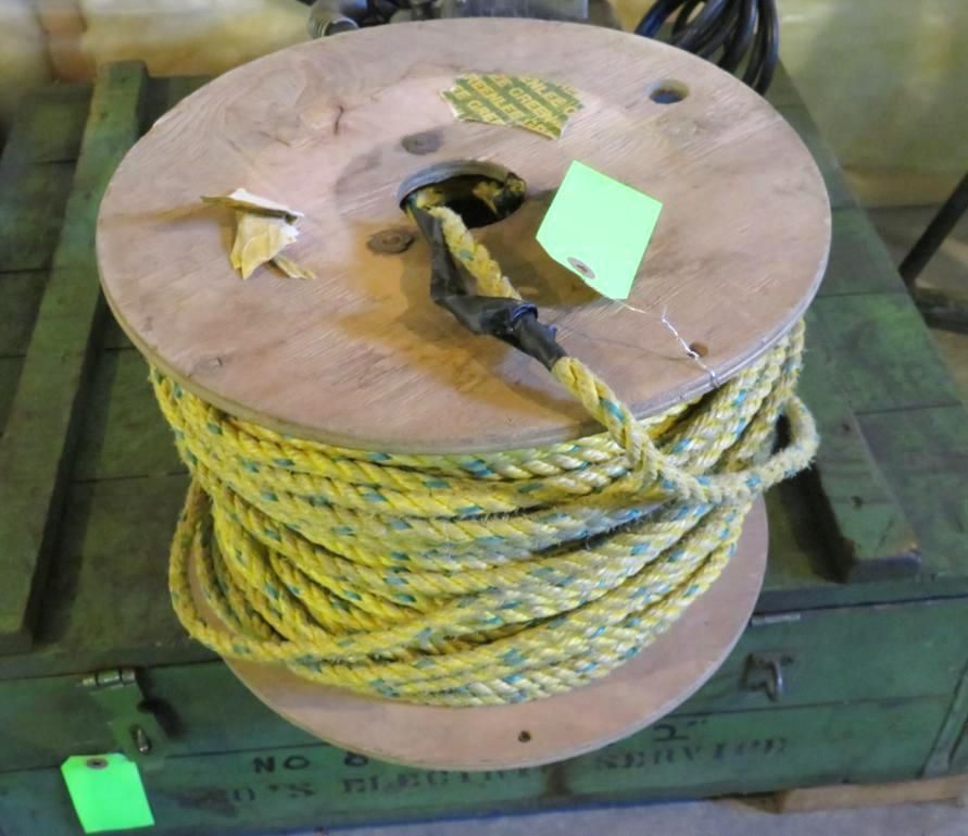 Yellow and blue rope coiled on a wooden spool, set on a green container.
