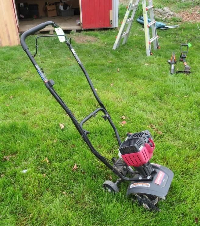 A red and black tiller on green grass.
