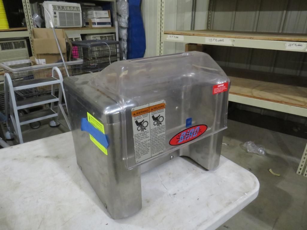 Stainless steel machine on a white table with warning labels.