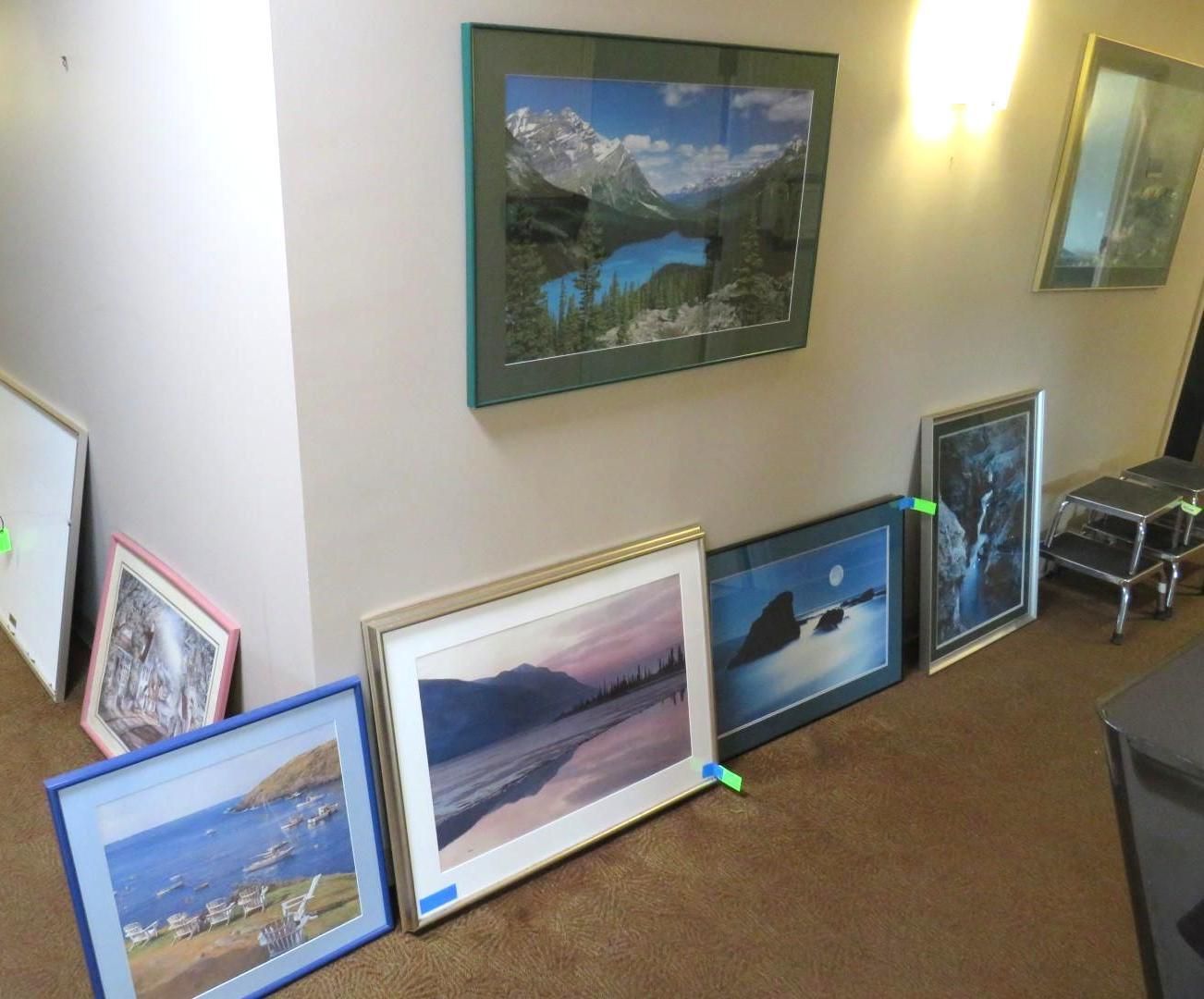 Artwork leaning against a wall, including landscape paintings in various frames.