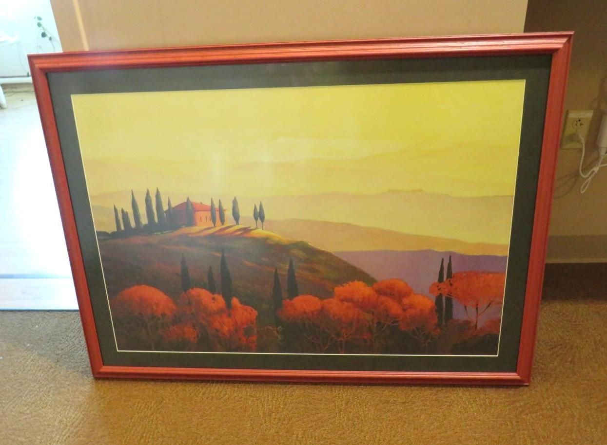 Framed landscape art of Tuscan hills, orange and yellow hues, red frame.