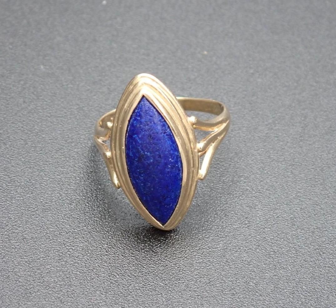 Gold ring with a marquise-shaped, deep blue gemstone set in the center.