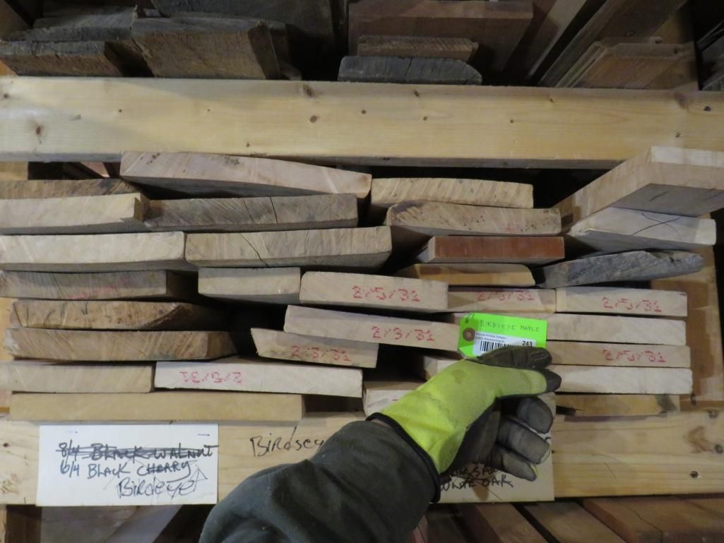 Hand with green glove scans a stack of lumber boards in a warehouse.