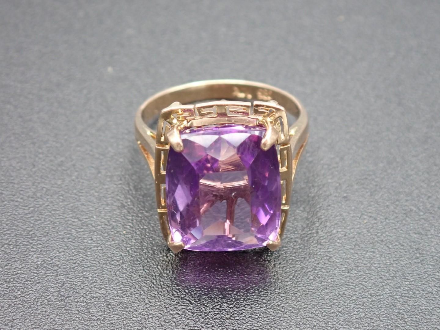 Gold ring with large square purple gemstone.