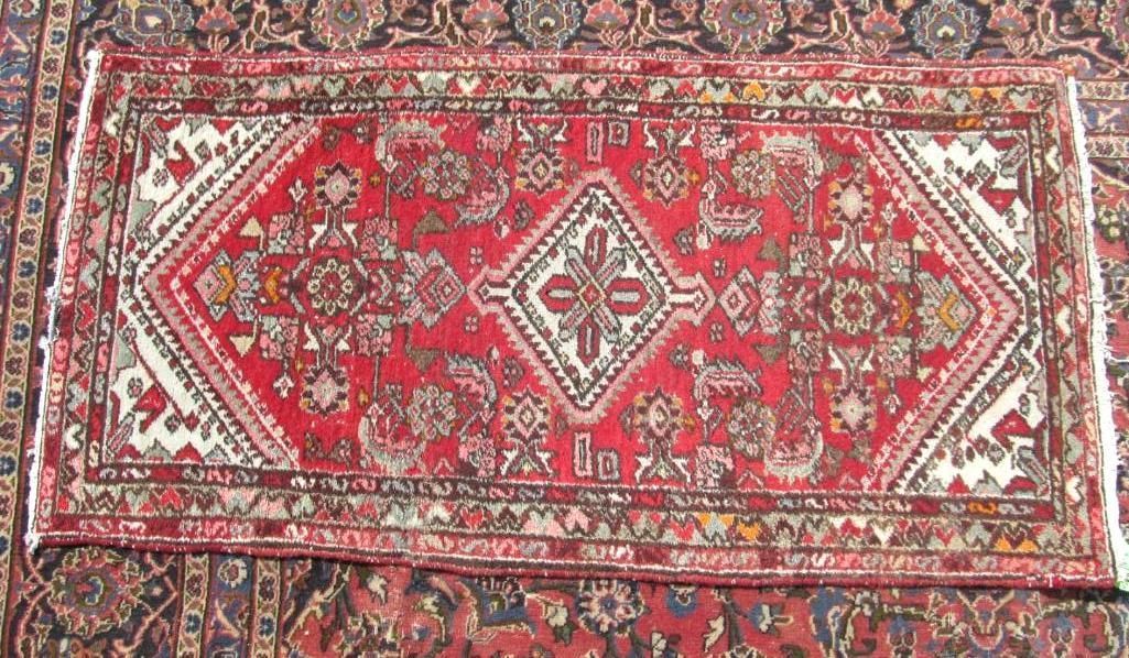 Red and white Oriental rug with geometric patterns and central diamond design.