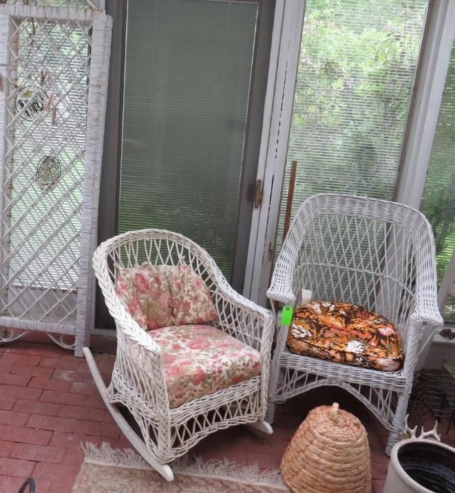 White wicker furniture in a sunroom: rocking chair and chair with floral cushions, screen, and a woven basket.