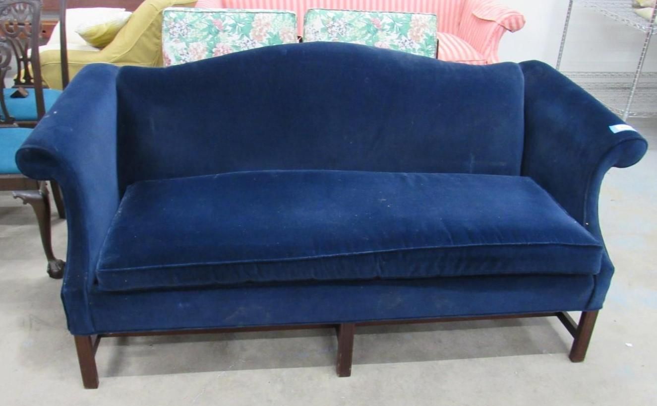 Blue velvet sofa with curved back and wooden legs.