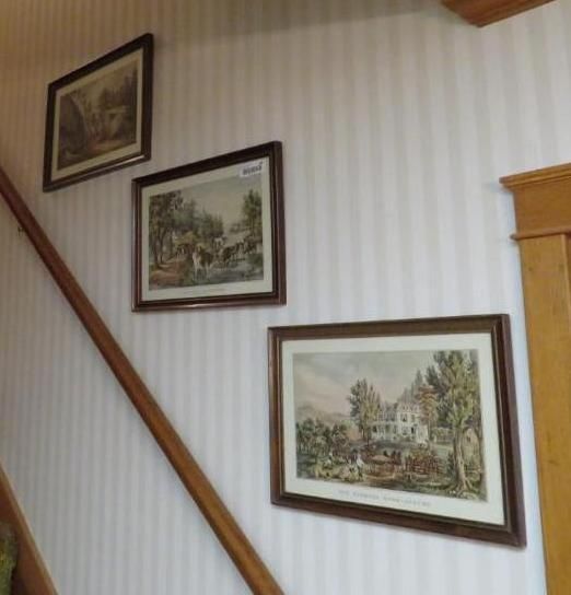 Three framed landscape prints on a striped wall above a wooden banister.