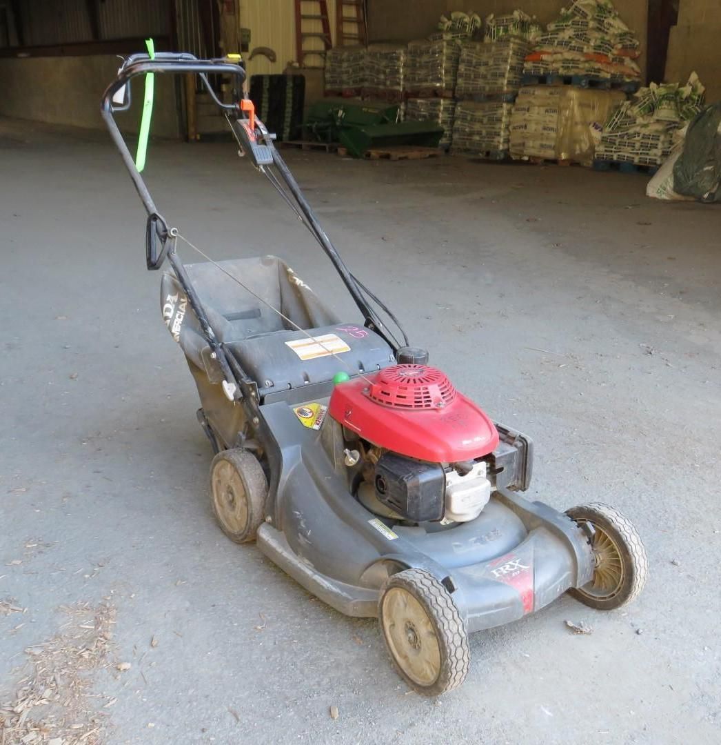 Gray Honda lawnmower on a concrete surface, with a red engine and grass catcher.