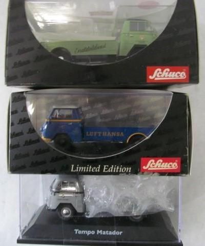 Three toy trucks in boxes, various colors, branded