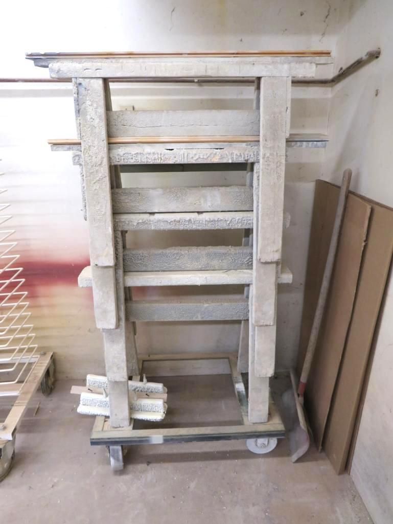 Gray wooden frame structure on a rolling cart, inside a workshop.