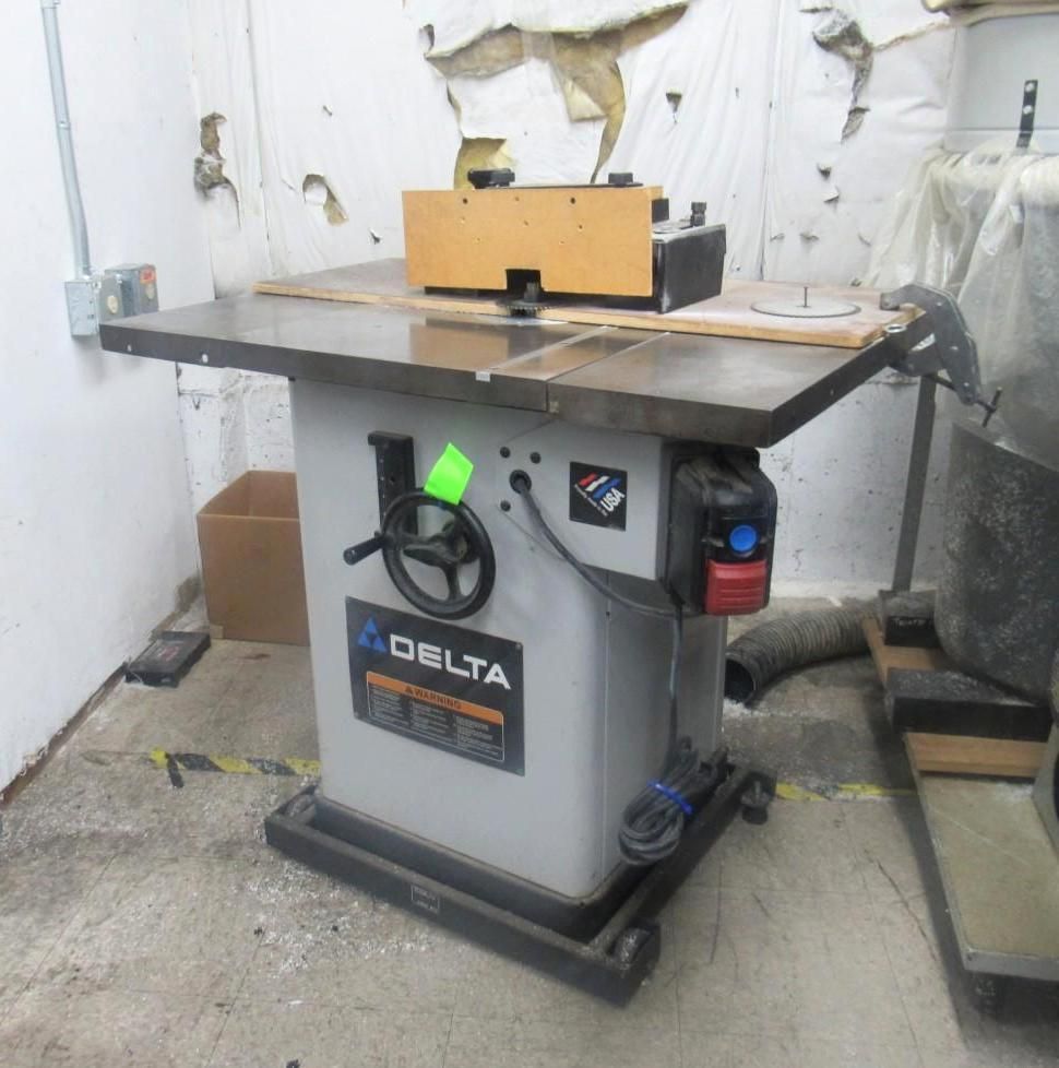 Delta router table in a workshop, grey with a wooden fence.