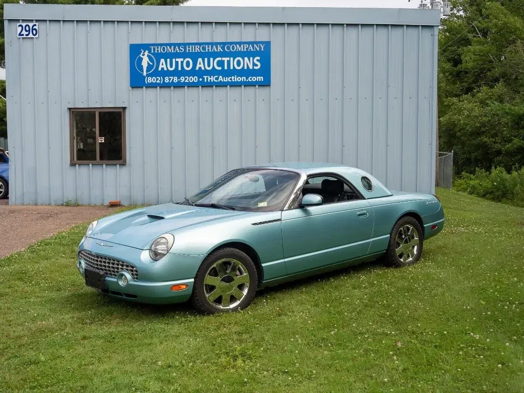 Teal Ford Thunderbird car parked in front of an auto auction building.