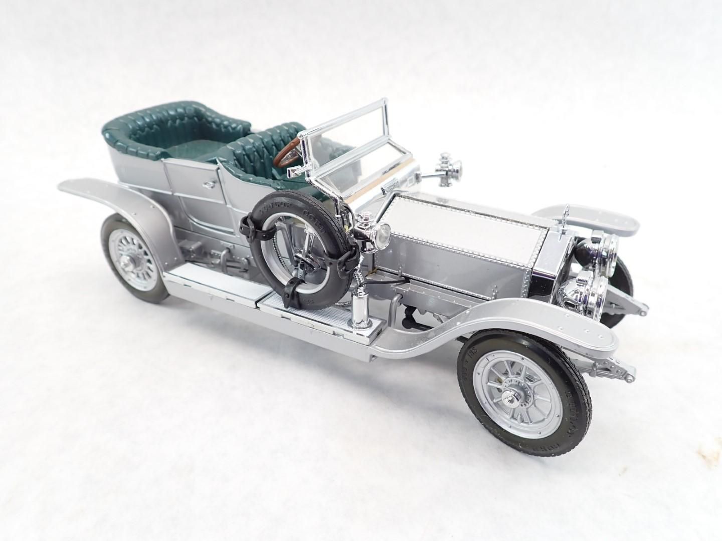 Silver Rolls Royce convertible model car with green seats, on a white background.