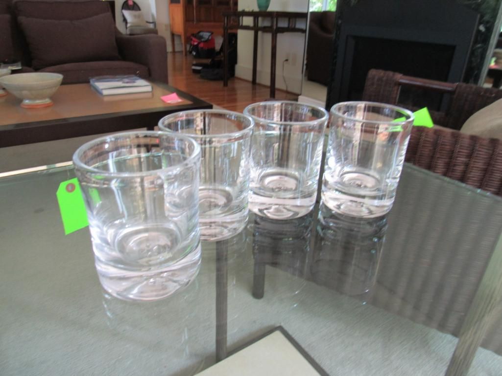 Four clear drinking glasses on a glass table.