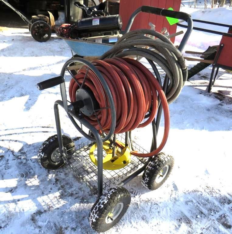 Gray cart holding coiled orange hose on snow.