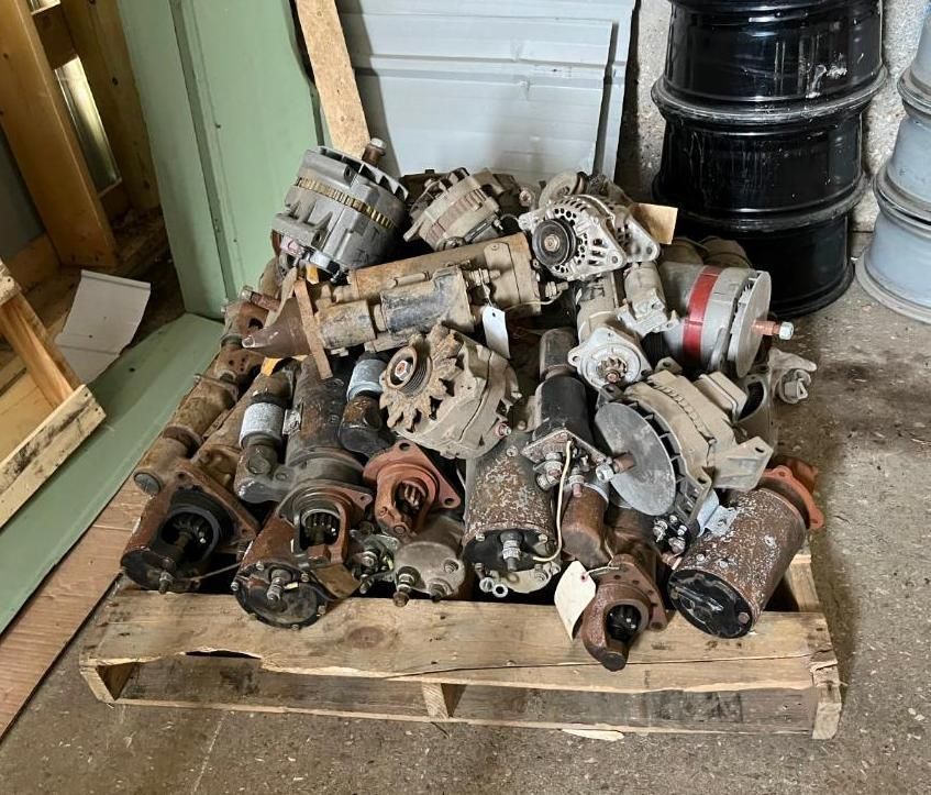 Pile of automotive parts on a wooden pallet; a variety of gears, starters, and alternators.