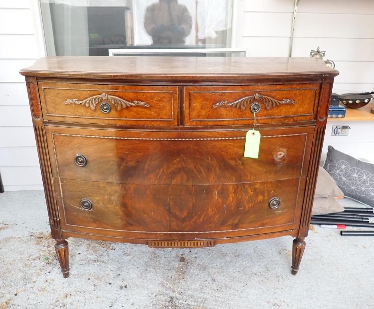 A vintage, brown wood dresser with two small top drawers and two large bottom drawers featuring decorative metal pulls.