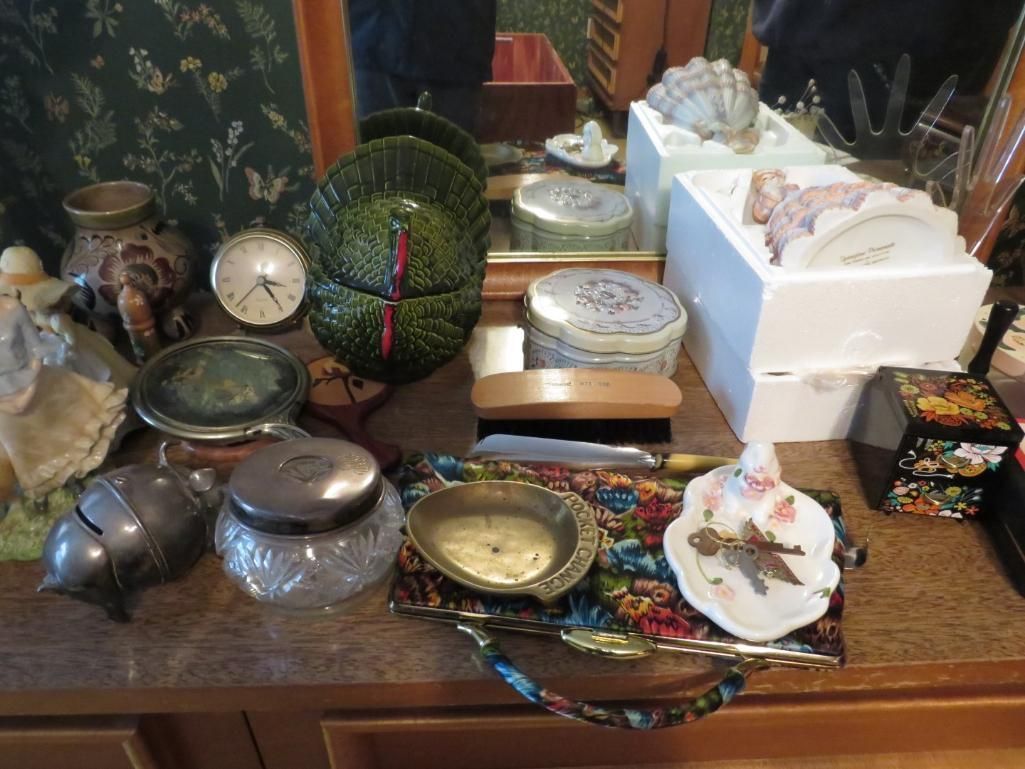 Tabletop display of vintage decorative items, including plates, boxes, a clock, and a brush.