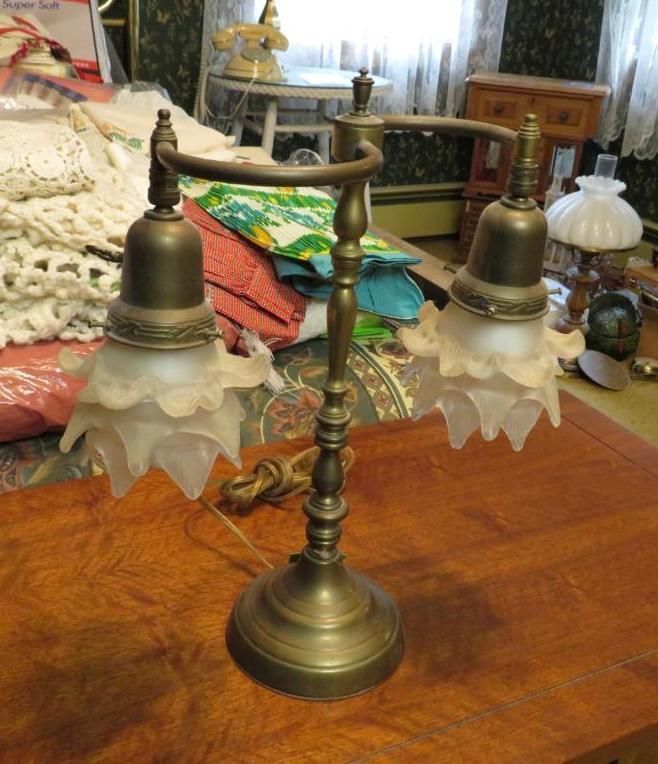 Brass desk lamp with two frosted glass shades, on a wooden table.