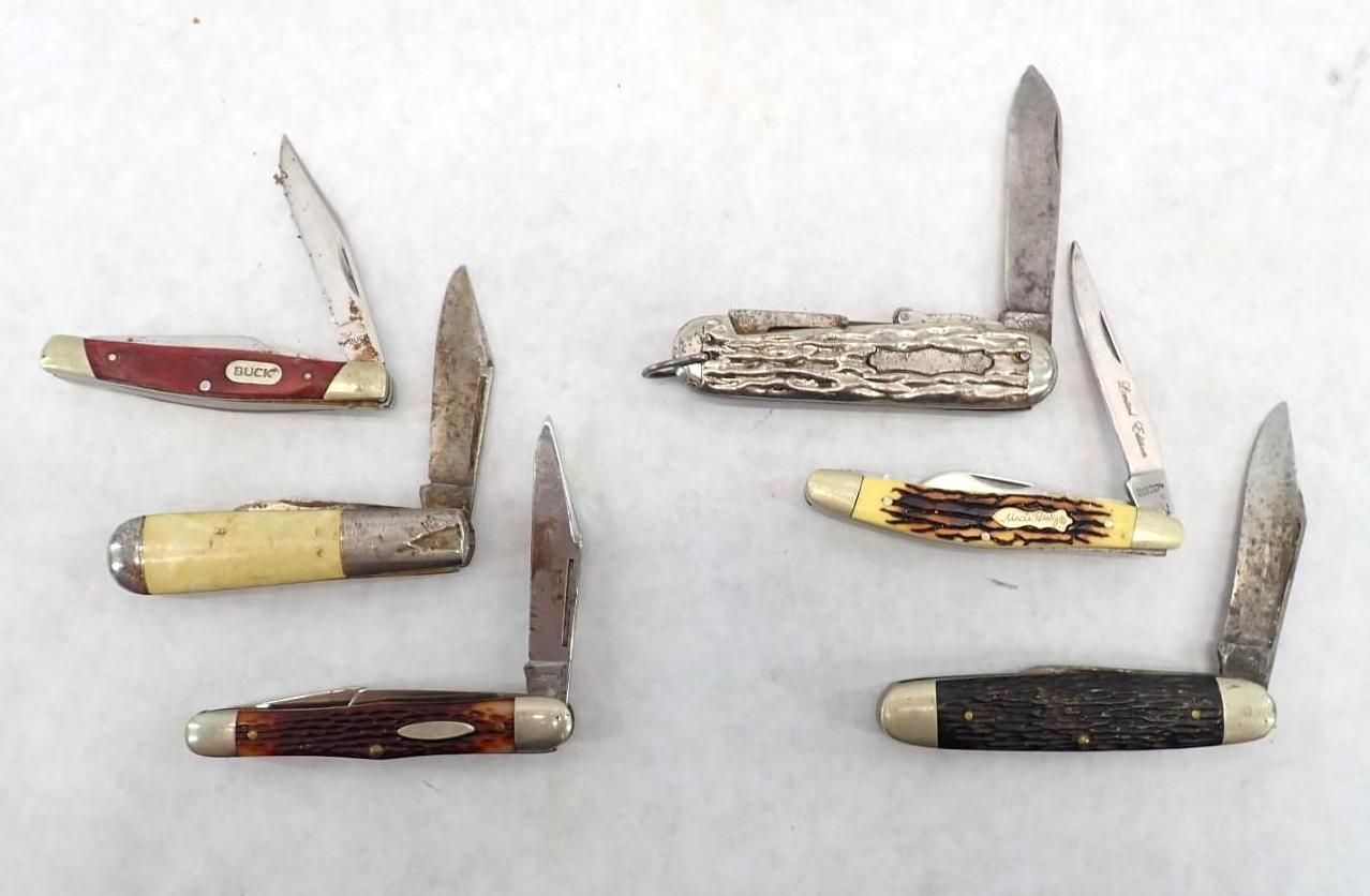 Six folding pocket knives with assorted handles and open blades on a white background