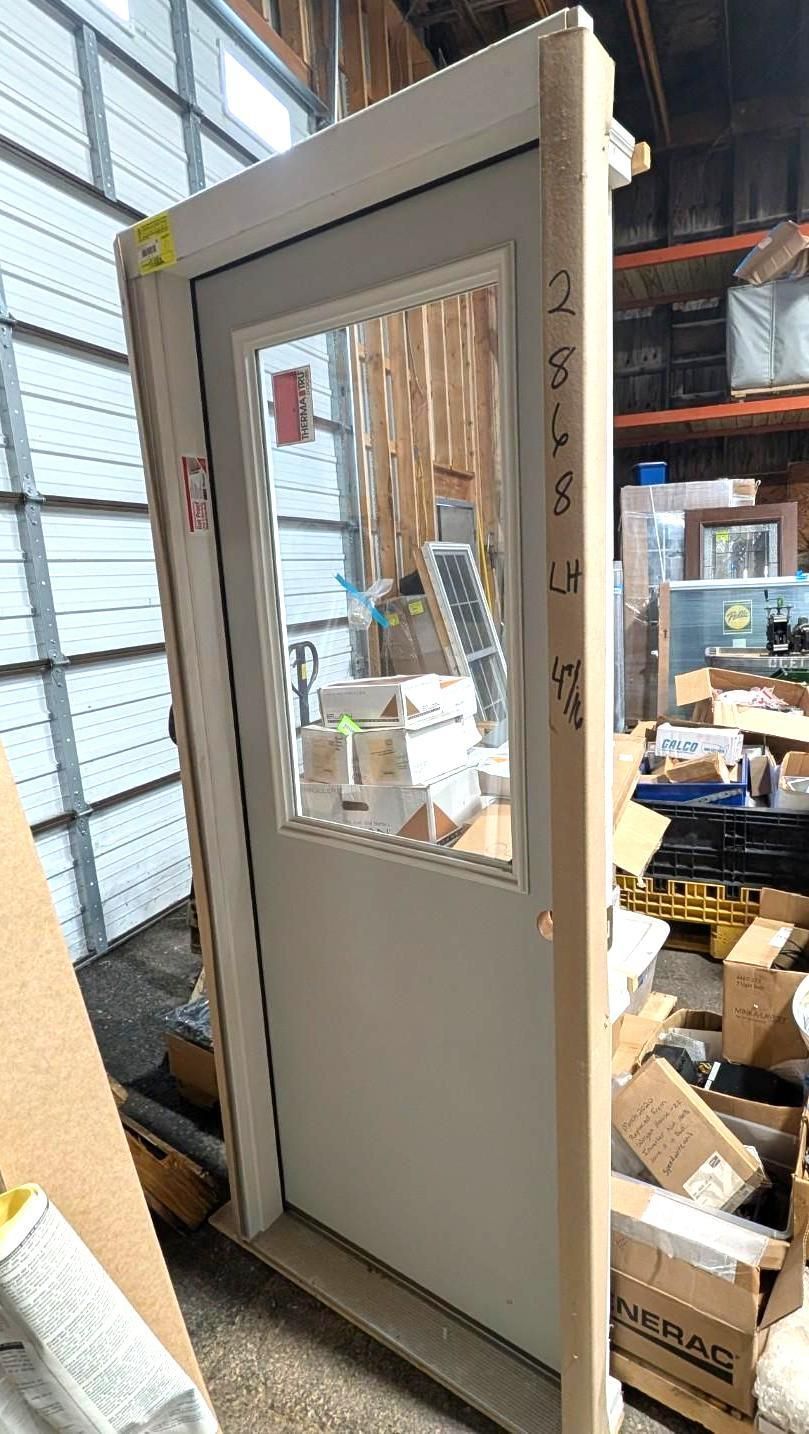 Gray door with a window leaning in a warehouse, surrounded by boxes and shelving