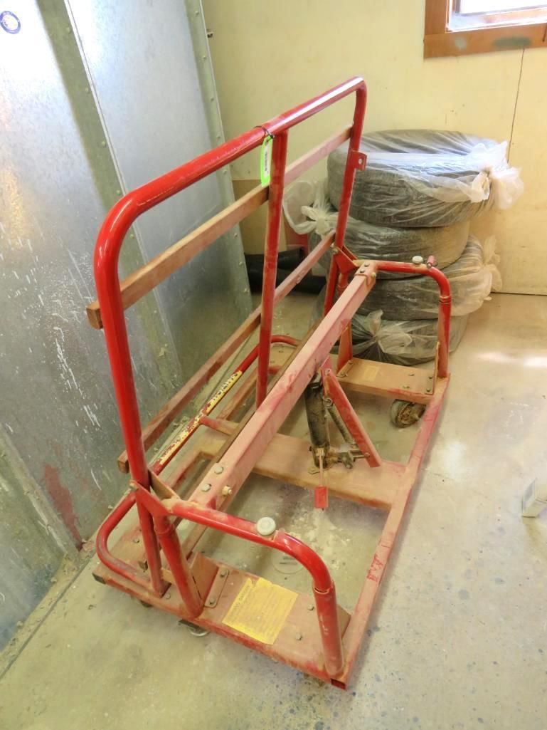 Red metal cart with wooden planks, against a wall.