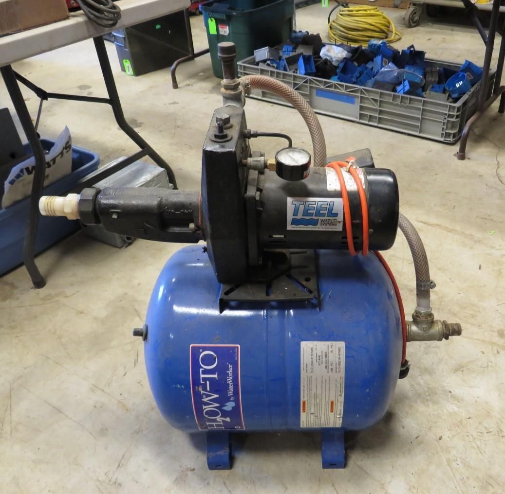 Blue water pump with pressure tank on a floor.