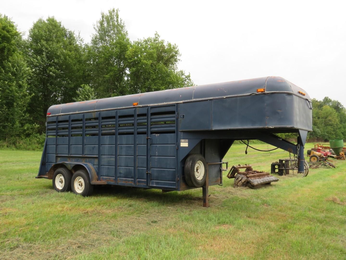 Blue livestock trailer parked in a grassy field.