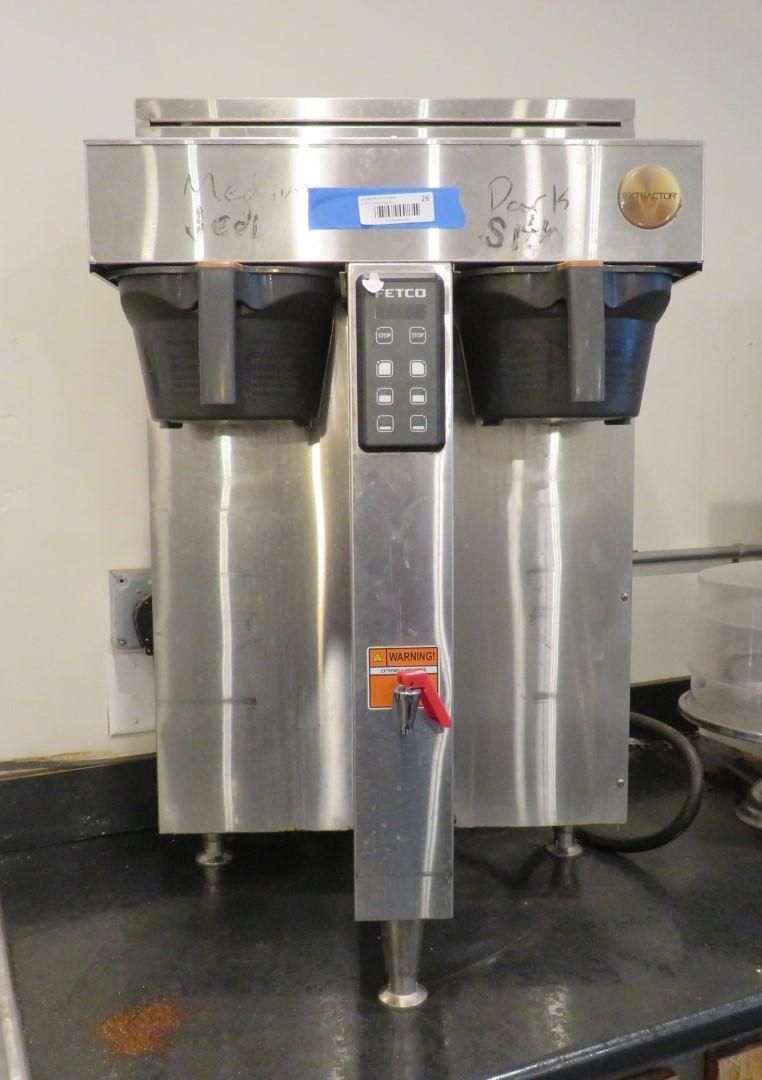 Stainless steel commercial coffee maker with two brewing units and a central dispenser.
