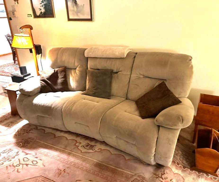 Beige reclining sofa with pillows in a living room.