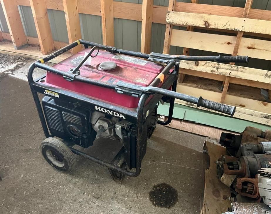 Honda generator with a red tank, black frame, and wheels.
