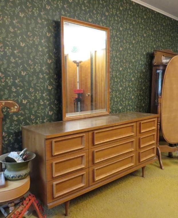 Wooden dresser with mirror against a floral wallpapered wall.
