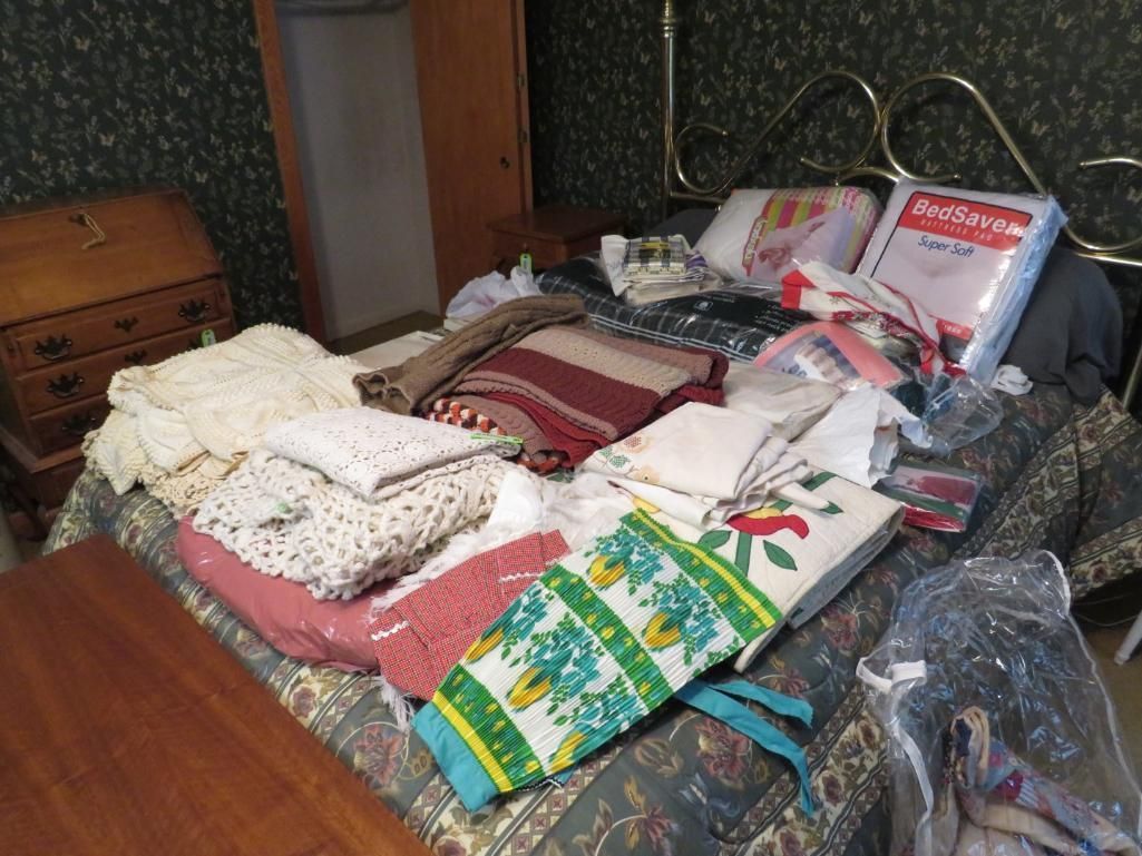 Bed covered with textiles, including blankets and embroidered fabrics.