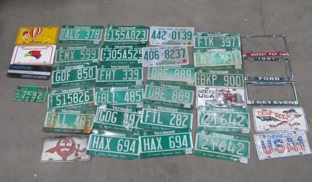 Pile of green and white license plates on a gray surface, some with frames, plus decorative plates.